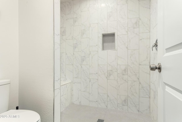 bathroom with toilet and tiled shower