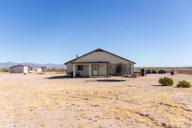 back of property featuring a mountain view and a trampoline