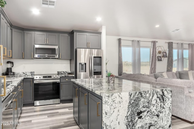 kitchen with stainless steel appliances, light hardwood / wood-style floors, a kitchen island, and gray cabinets