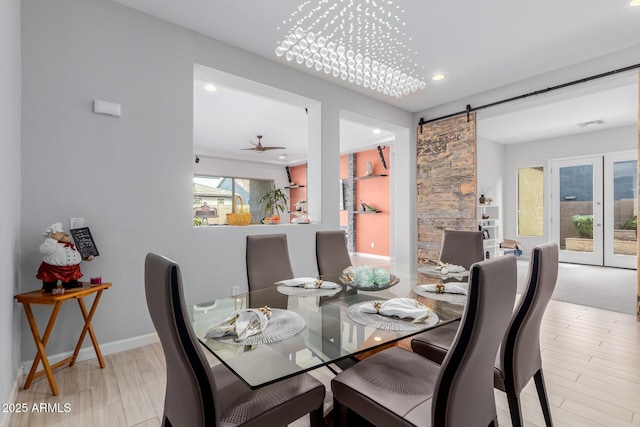 dining area featuring ceiling fan, a barn door, and light hardwood / wood-style floors