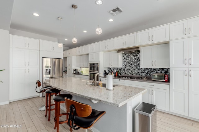 kitchen featuring pendant lighting, white cabinetry, and a center island with sink