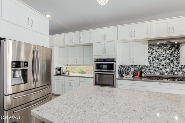 kitchen with white cabinetry, tasteful backsplash, light stone countertops, and appliances with stainless steel finishes