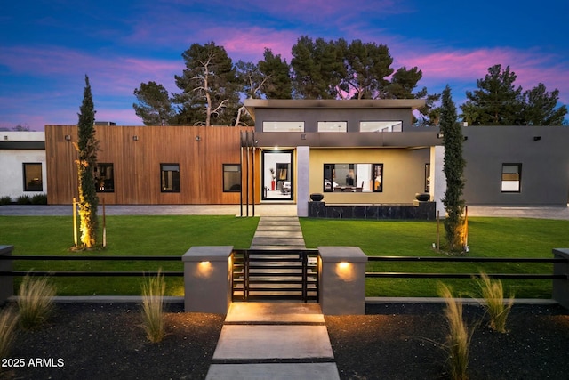 contemporary home with stucco siding, a lawn, and a fenced front yard