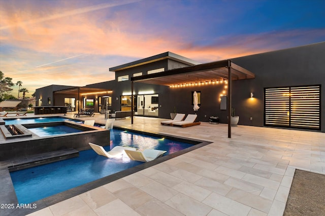 outdoor pool with a patio area and an in ground hot tub