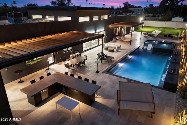 pool at dusk featuring a community pool, a jacuzzi, a patio, and fence