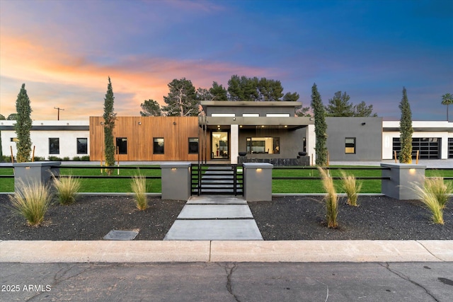 modern home featuring a gate, a lawn, a fenced front yard, and stucco siding