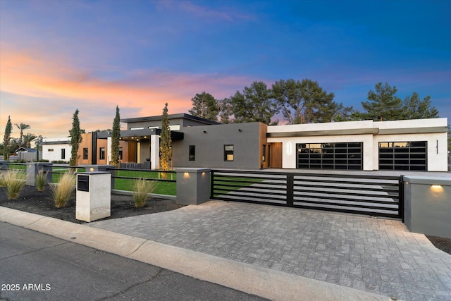 contemporary house with a gate, a fenced front yard, and stucco siding