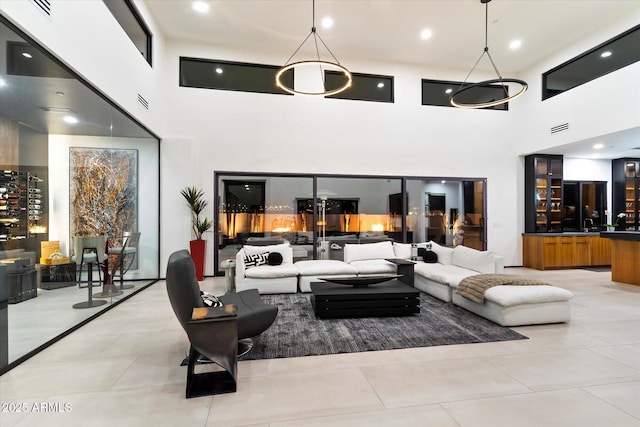 living area with light tile patterned floors, visible vents, recessed lighting, and a towering ceiling