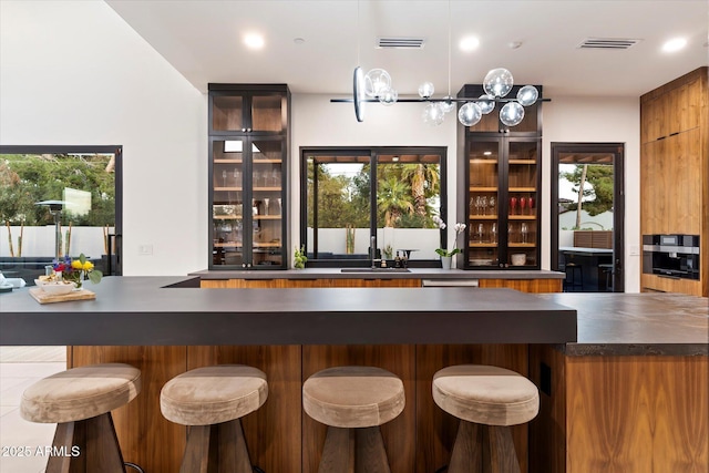 bar featuring a community bar, visible vents, oven, and a sink