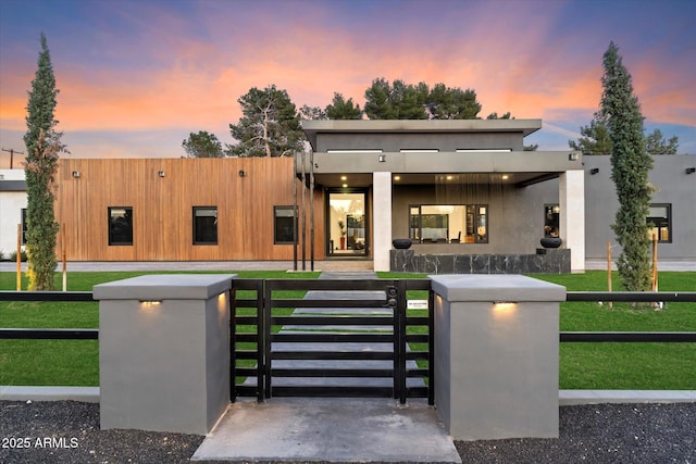 contemporary house with a fenced front yard, stucco siding, a front lawn, and a gate