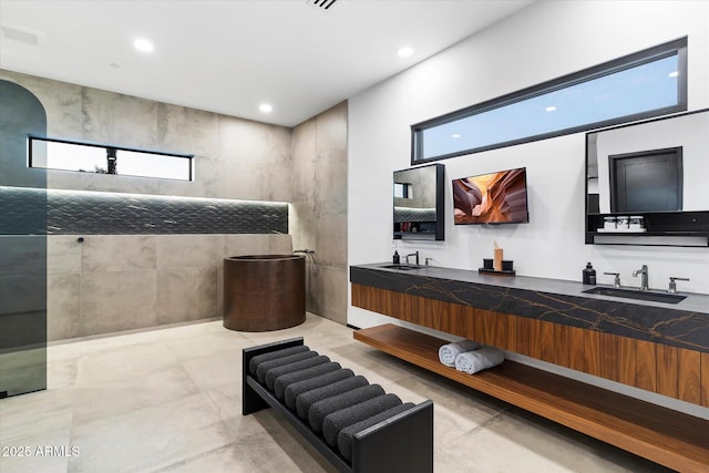 bathroom featuring double vanity, recessed lighting, a walk in shower, and a sink