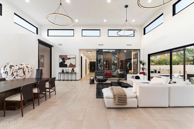 living area featuring light tile patterned floors, a towering ceiling, and recessed lighting