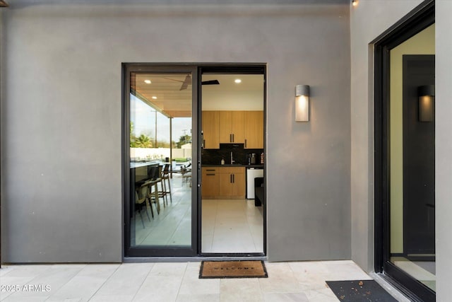 entrance to property with a sink and stucco siding