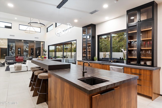 bar featuring a sink, decorative light fixtures, dishwasher, and light tile patterned floors