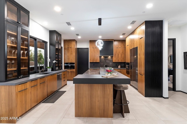 kitchen with dark countertops, tasteful backsplash, a kitchen island, modern cabinets, and a sink