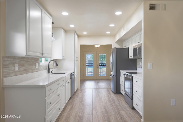 kitchen with white cabinetry, sink, french doors, backsplash, and appliances with stainless steel finishes