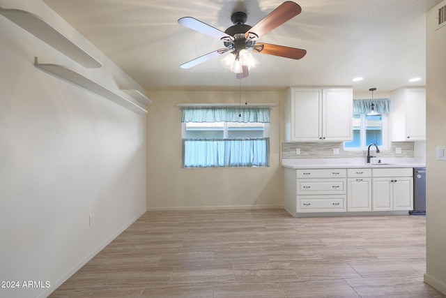 kitchen featuring backsplash, sink, stainless steel dishwasher, decorative light fixtures, and white cabinetry