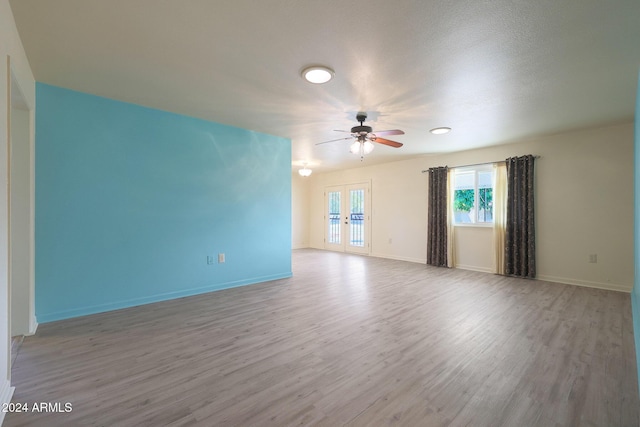 spare room with ceiling fan, french doors, and light wood-type flooring