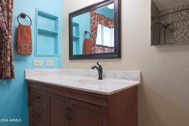 bathroom featuring built in shelves, vanity, and a tile shower