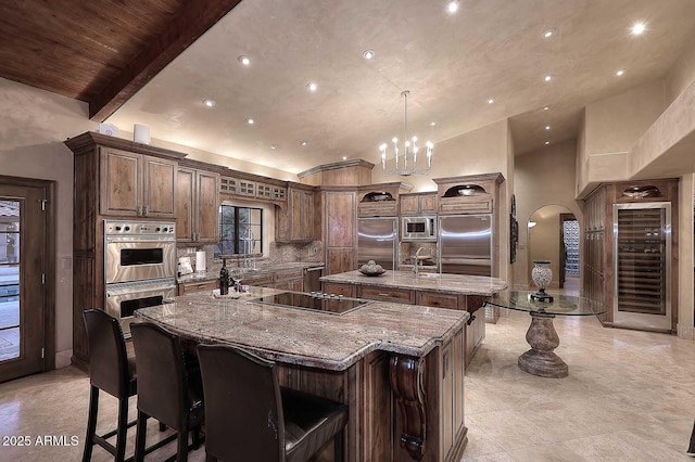 10365 E Paradise Dr, Scottsdale, AZ 85260 - kitchen featuring a large island, light stone counters, tasteful backsplash, arched walkways, and built in appliances