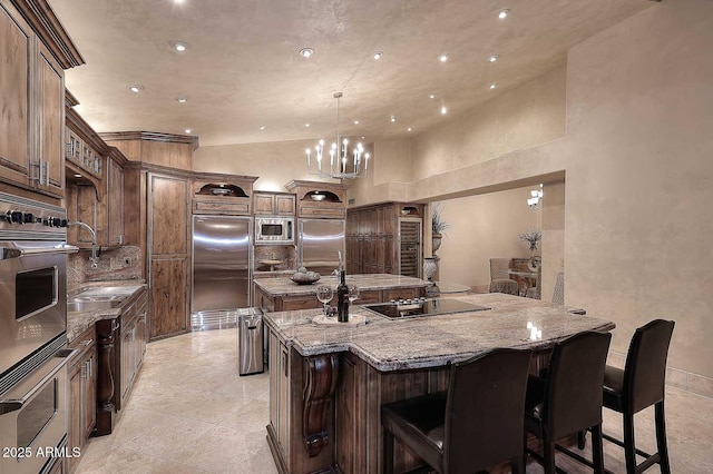 10365 E Paradise Dr, Scottsdale, AZ 85260 - kitchen featuring a breakfast bar area, light stone countertops, a center island with sink, a sink, and built in appliances