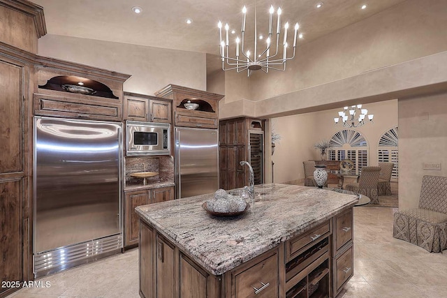10365 E Paradise Dr, Scottsdale, AZ 85260 - kitchen featuring light stone counters, built in appliances, an inviting chandelier, and open floor plan