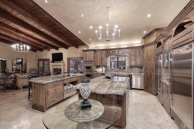 10365 E Paradise Dr, Scottsdale, AZ 85260 - kitchen with light stone counters, a large island with sink, appliances with stainless steel finishes, a kitchen breakfast bar, and a chandelier