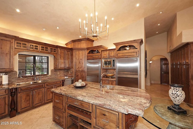 10365 E Paradise Dr, Scottsdale, AZ 85260 - kitchen with a center island with sink, open shelves, arched walkways, light tile patterned floors, and built in appliances