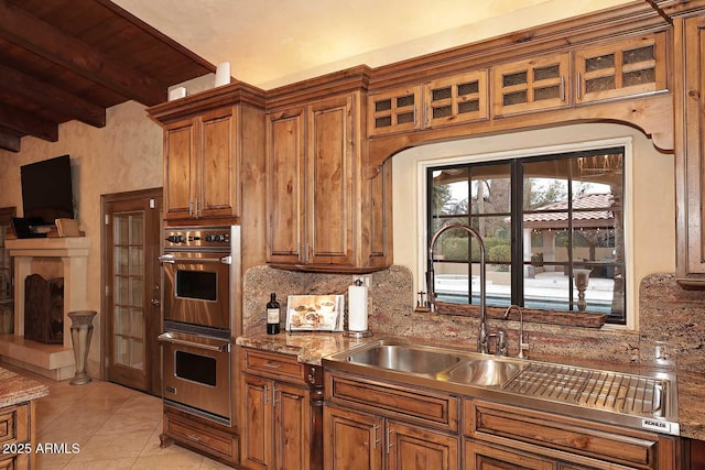 10365 E Paradise Dr, Scottsdale, AZ 85260 - kitchen with brown cabinetry, light tile patterned floors, double oven, and tasteful backsplash