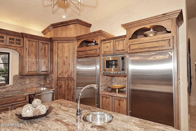 10365 E Paradise Dr, Scottsdale, AZ 85260 - kitchen with tasteful backsplash, built in appliances, brown cabinetry, and light stone countertops