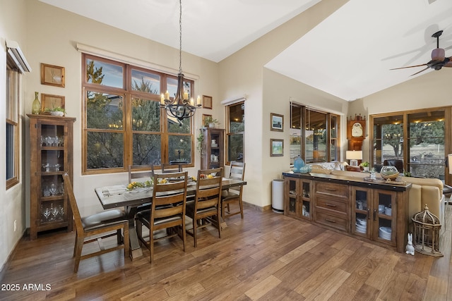 dining space featuring vaulted ceiling, ceiling fan with notable chandelier, and hardwood / wood-style floors