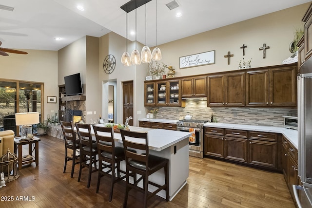 kitchen featuring a kitchen island, a breakfast bar, backsplash, high end stainless steel range oven, and hanging light fixtures