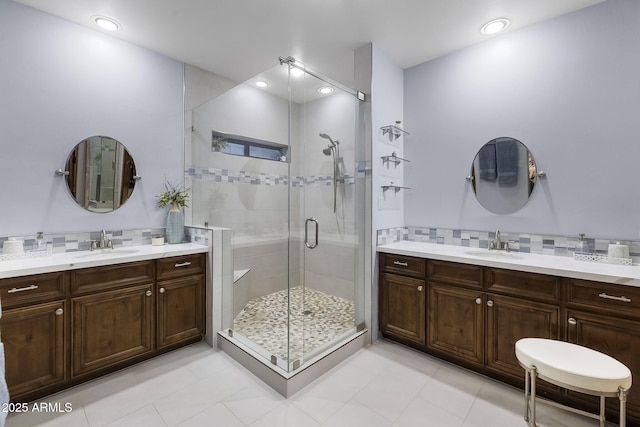 bathroom with tasteful backsplash, vanity, tile patterned flooring, and a shower with door