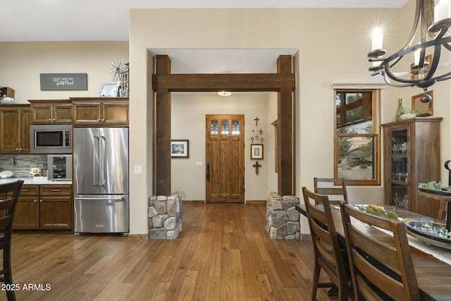 kitchen with an inviting chandelier, tasteful backsplash, stainless steel appliances, and light hardwood / wood-style flooring