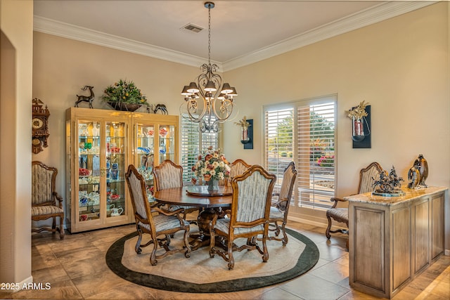 dining area with light tile patterned flooring, ornamental molding, and an inviting chandelier