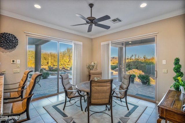 tiled dining room with ceiling fan and crown molding