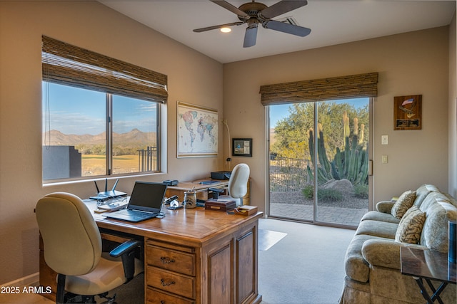 carpeted office space with a mountain view and ceiling fan