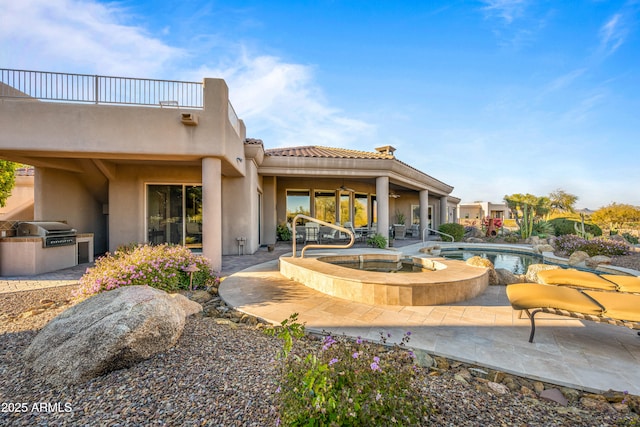 back of house with area for grilling, a patio area, a balcony, and a swimming pool with hot tub