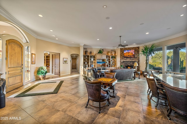 interior space featuring a stone fireplace, ceiling fan, and ornamental molding