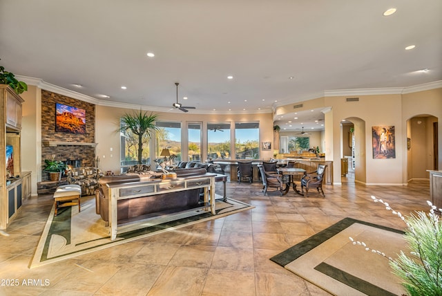 living room with ceiling fan, a fireplace, and ornamental molding