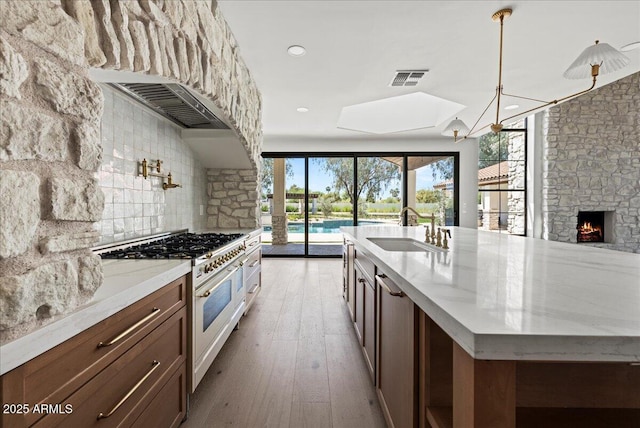10755 E Cholla Ln, Scottsdale, AZ 85259 - kitchen featuring gas range, a sink, backsplash, light stone counters, and light wood-style floors