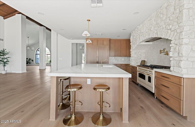 10755 E Cholla Ln, Scottsdale, AZ 85259 - kitchen with range with two ovens, light wood finished floors, decorative backsplash, a sink, and a large island