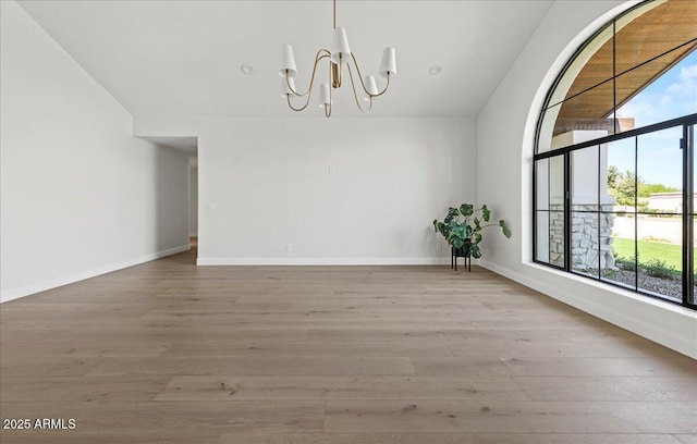 10755 E Cholla Ln, Scottsdale, AZ 85259 - empty room featuring a chandelier, wood finished floors, and baseboards