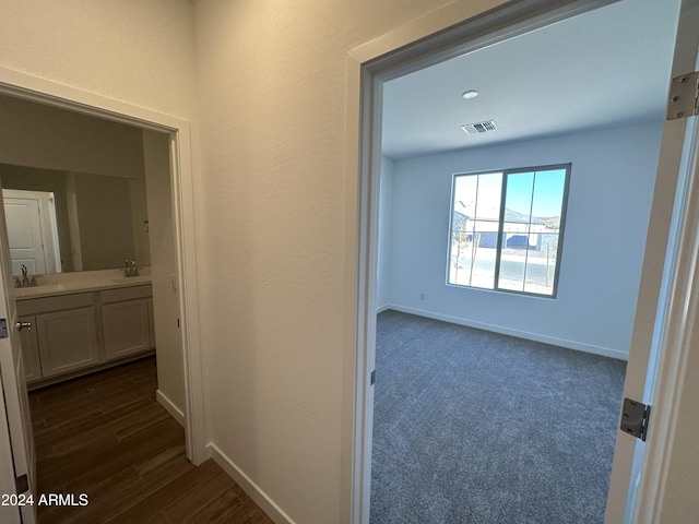 hall featuring sink and dark colored carpet