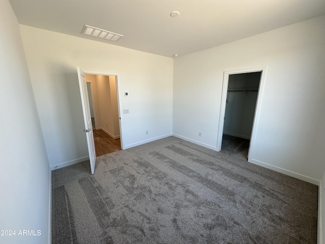 unfurnished bedroom with a walk in closet, carpet floors, and a closet