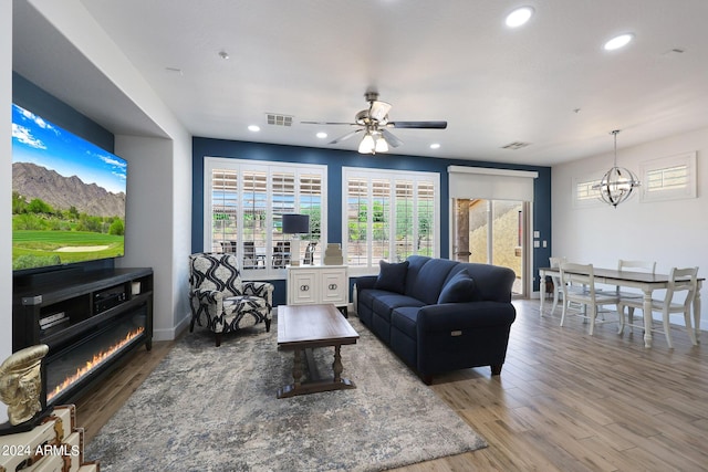 living room with wood-type flooring and ceiling fan with notable chandelier