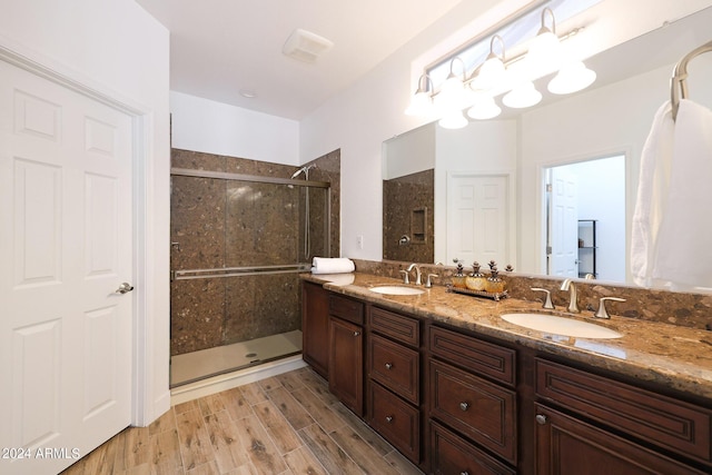 bathroom featuring a shower with door and vanity