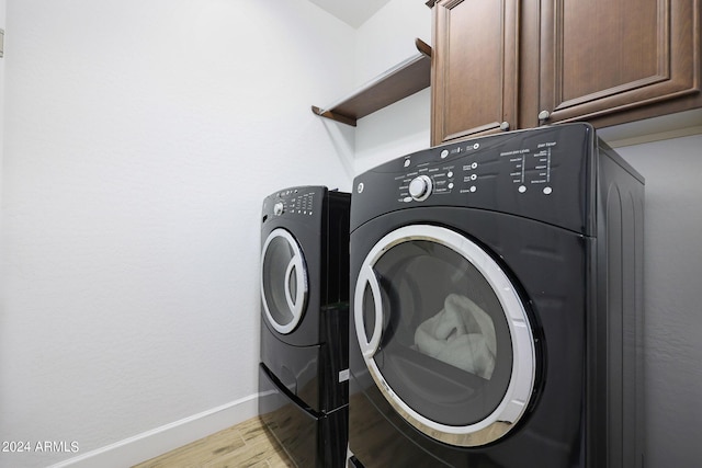 clothes washing area with cabinets, separate washer and dryer, and light wood-type flooring