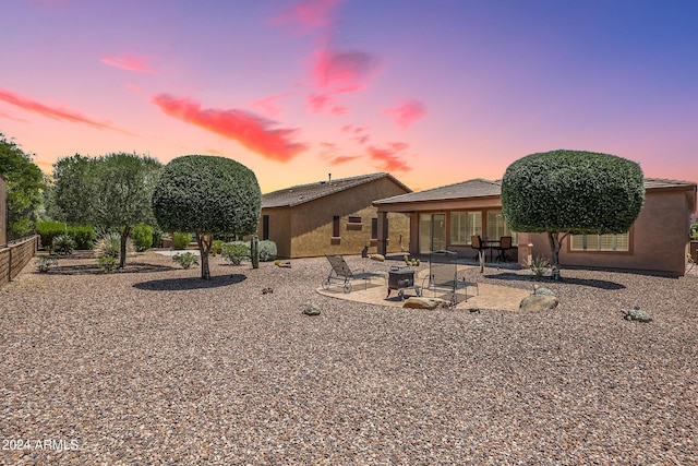 back house at dusk with an outdoor fire pit and a patio area