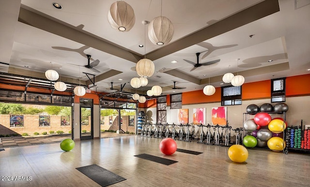 gym with hardwood / wood-style floors, a raised ceiling, and ceiling fan